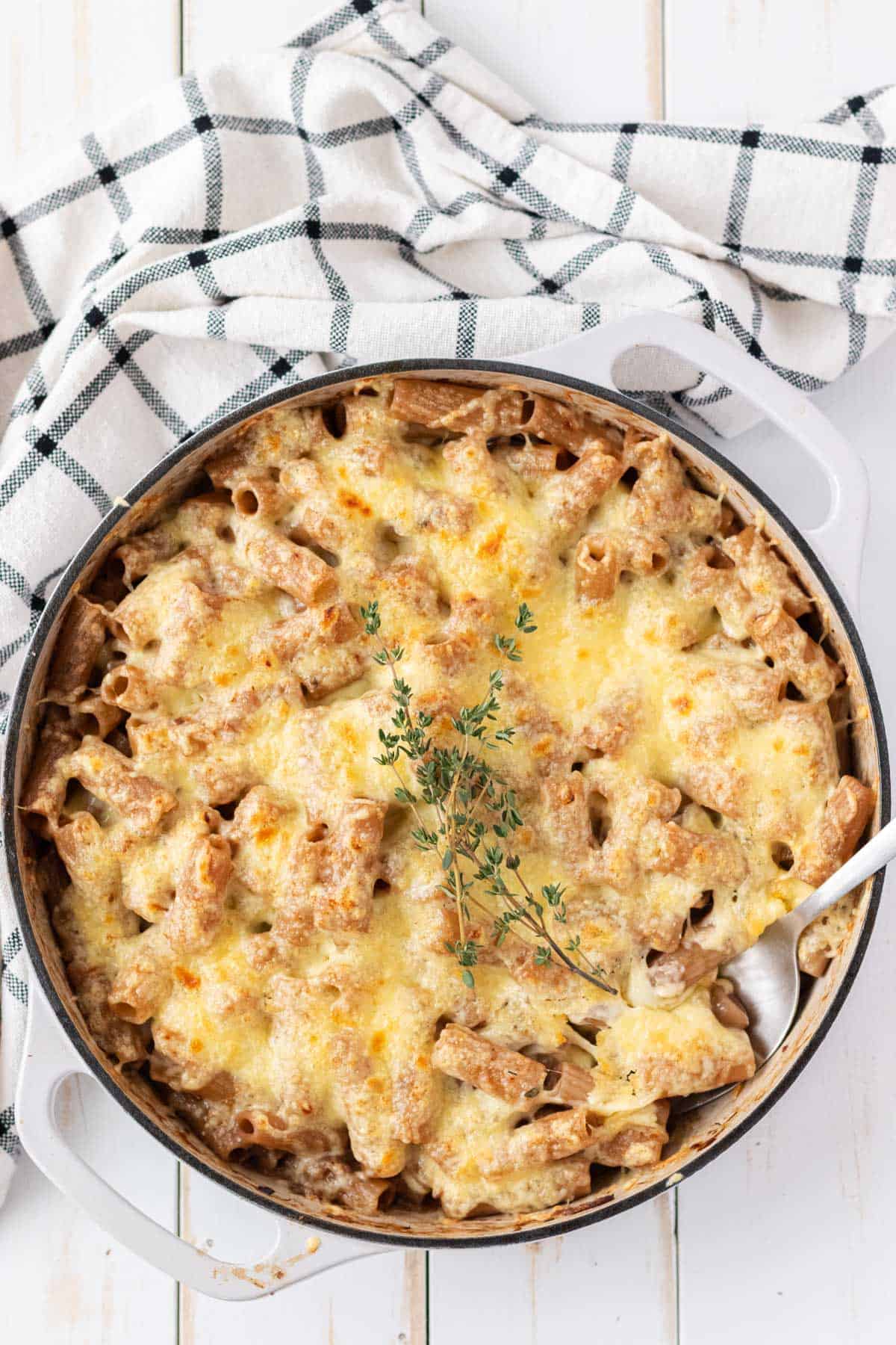 A large enamelled cast iron sauté pan filled with french onion soup pasta.