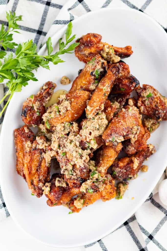 A white serving dish filled with garlic parmesan wings.