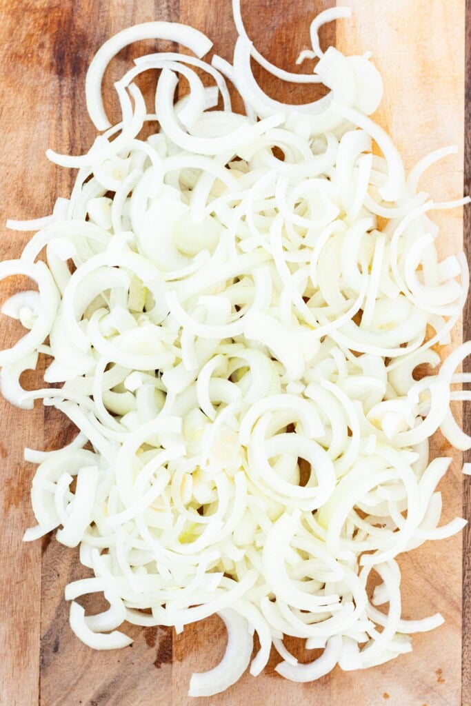 Sliced onions on a wooden cutting board.