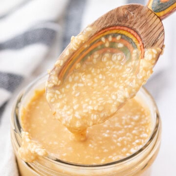 Roasted sesame dressing dripping off of a spoon.