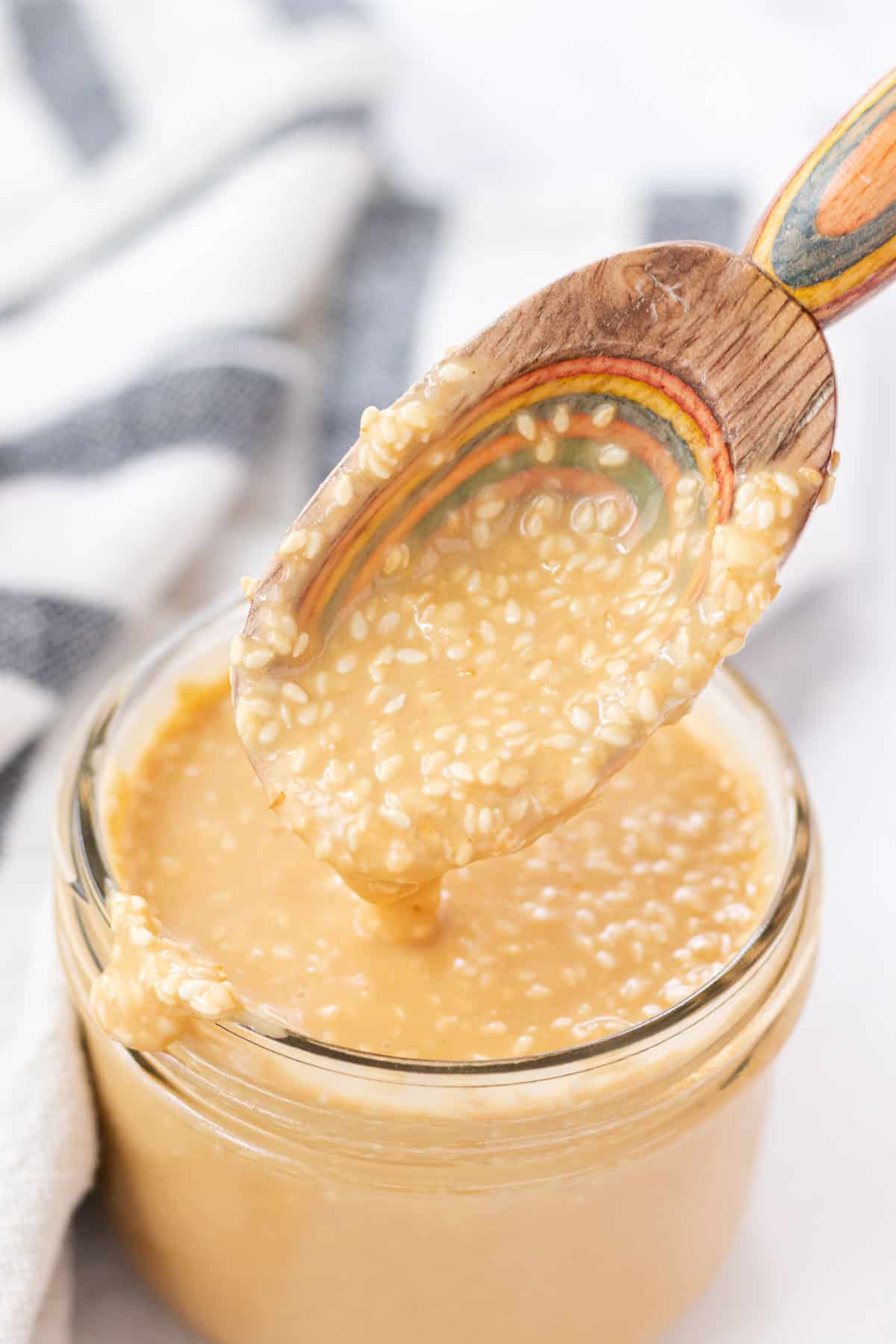 Roasted sesame dressing dripping off of a spoon.