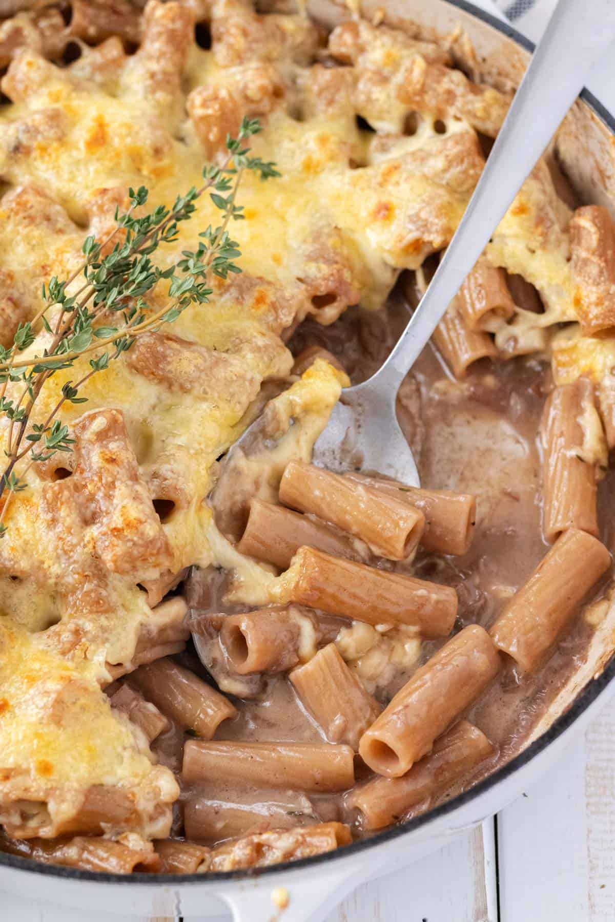 A silver serving spoon taking a scoop of pasta and cheese.