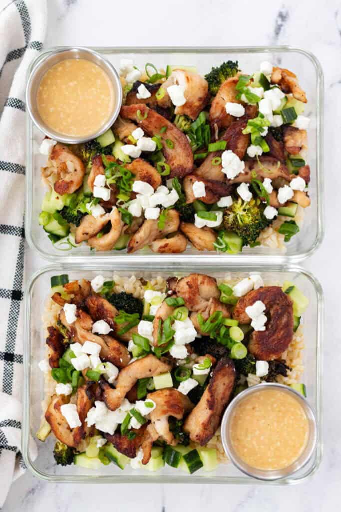 Chicken bowls packaged in meal prep containers with sesame sauce on the side.