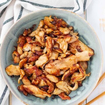 A blue bowl filled with velvet chicken with a pair of chopsticks on the side.
