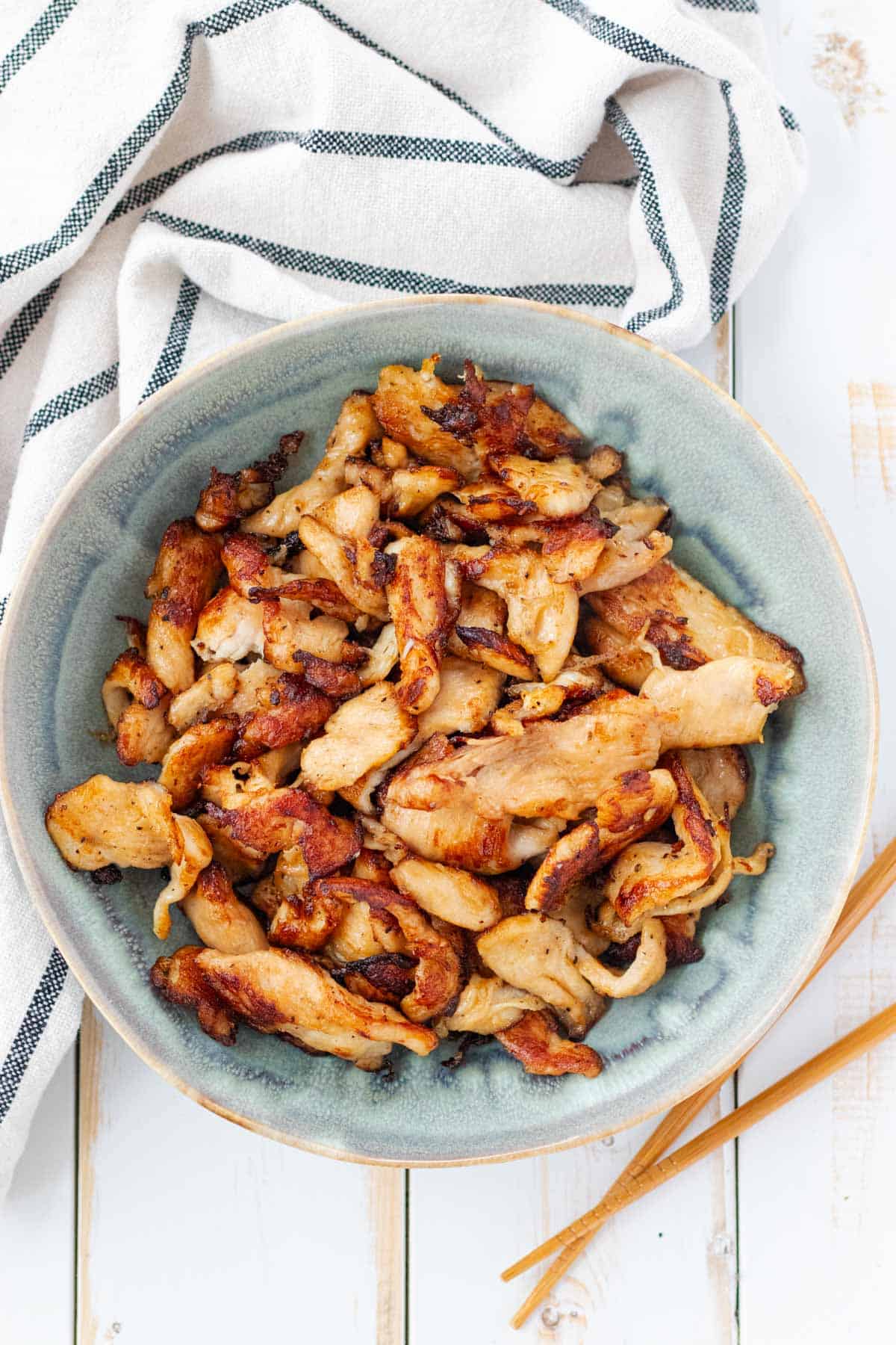 A blue bowl filled with velvet chicken with a pair of chopsticks on the side.