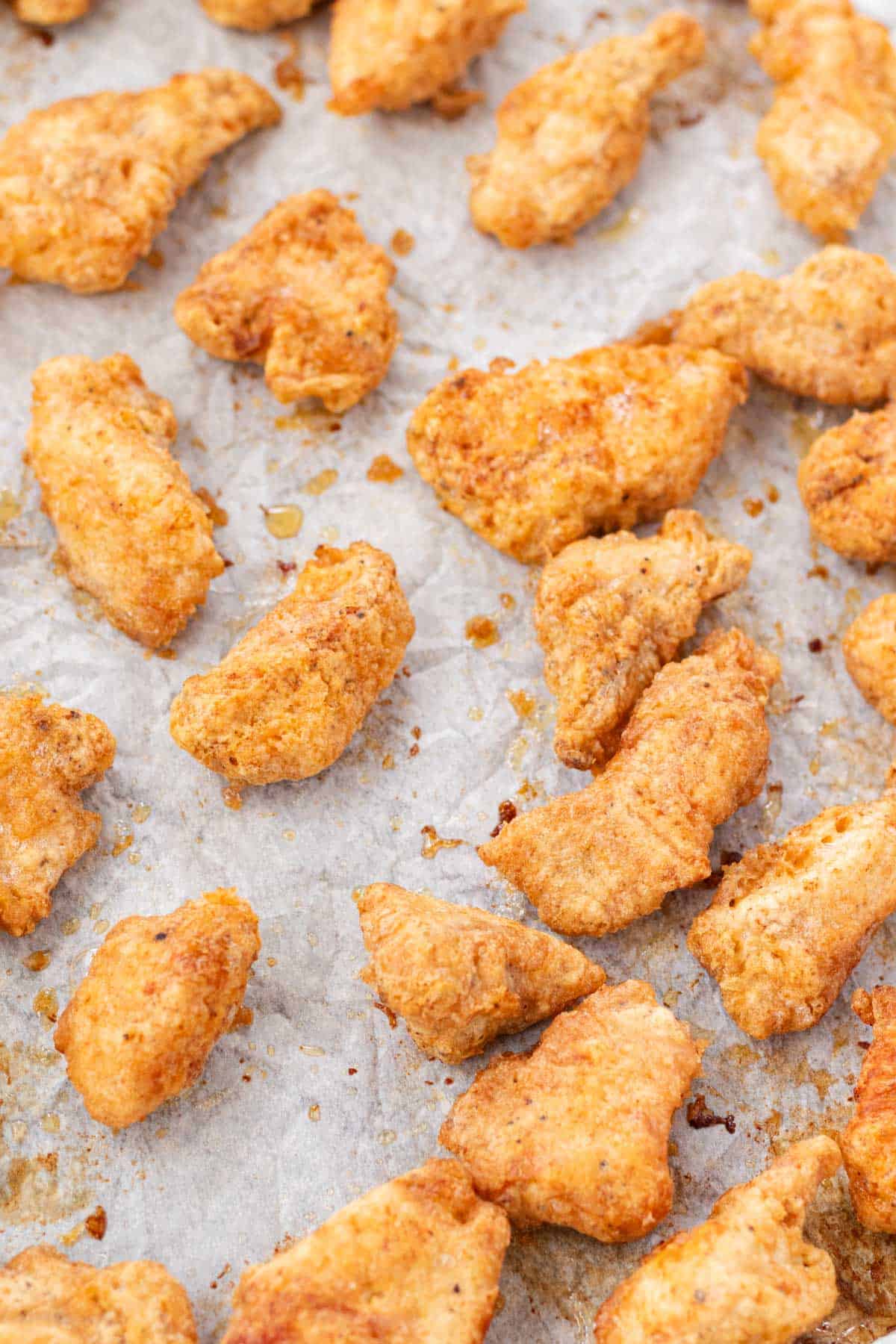 Golden brown crispy chicken pieces on a baking sheet after baking.