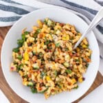A white bowl full of buffalo chickpea pasta salad on a wooden board.