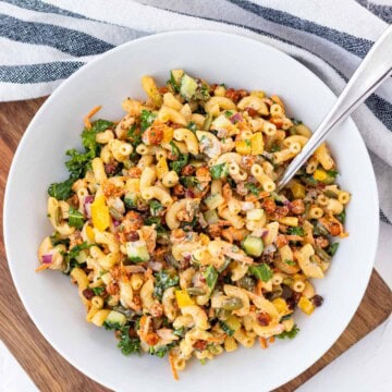 A white bowl full of buffalo chickpea pasta salad on a wooden board.