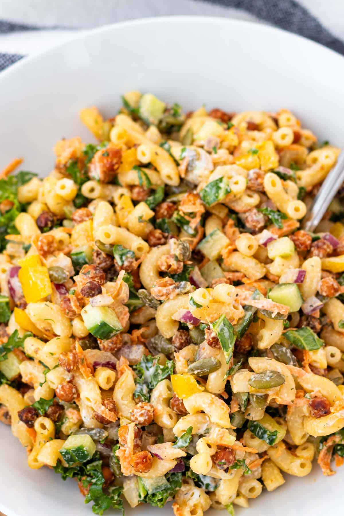 Kale pasta salad in a white bowl with a fork.