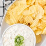 French onion chip dip in a white bowl with ruffle chips on the side.