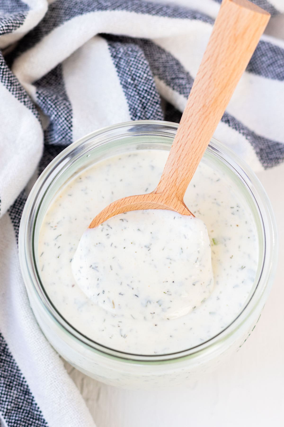 A wooden spoonful of ranch dressing in a mason jar.
