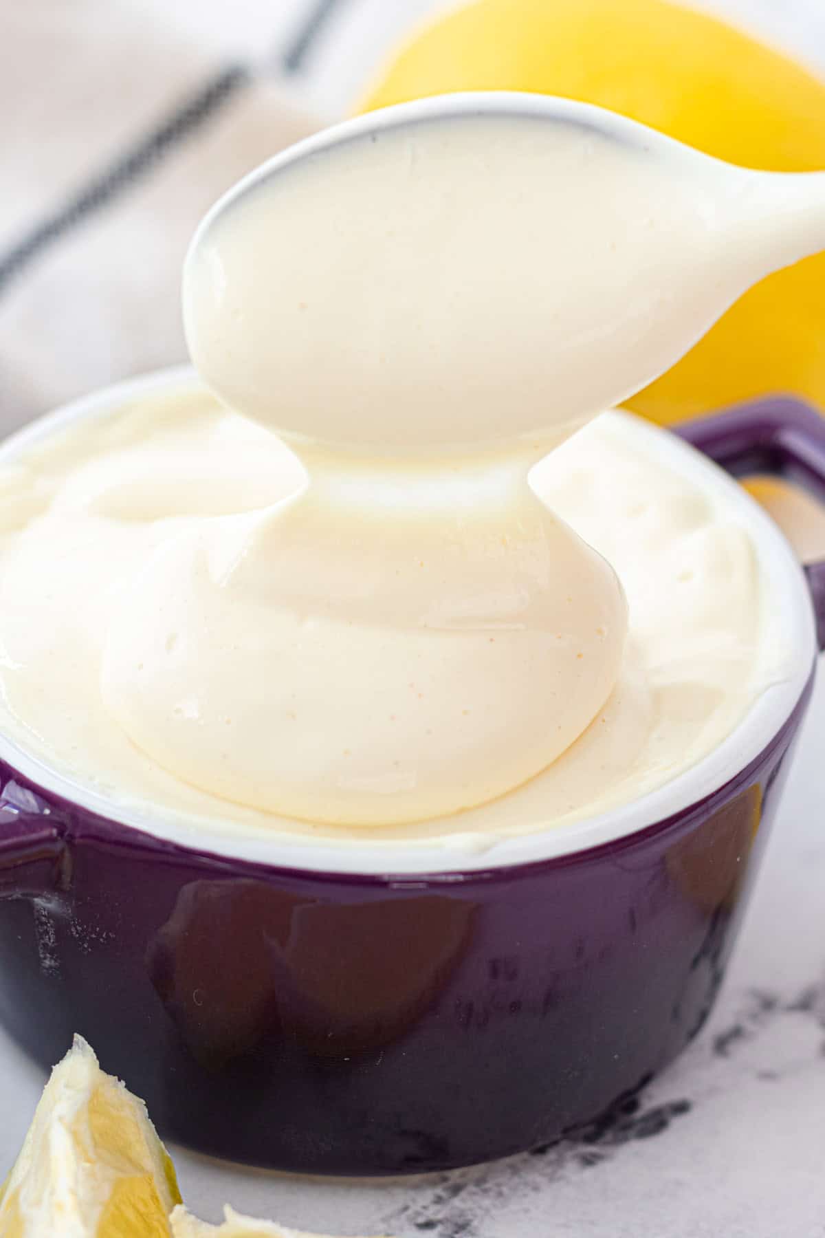 Homemade mayonnaise falling off of a spoon.