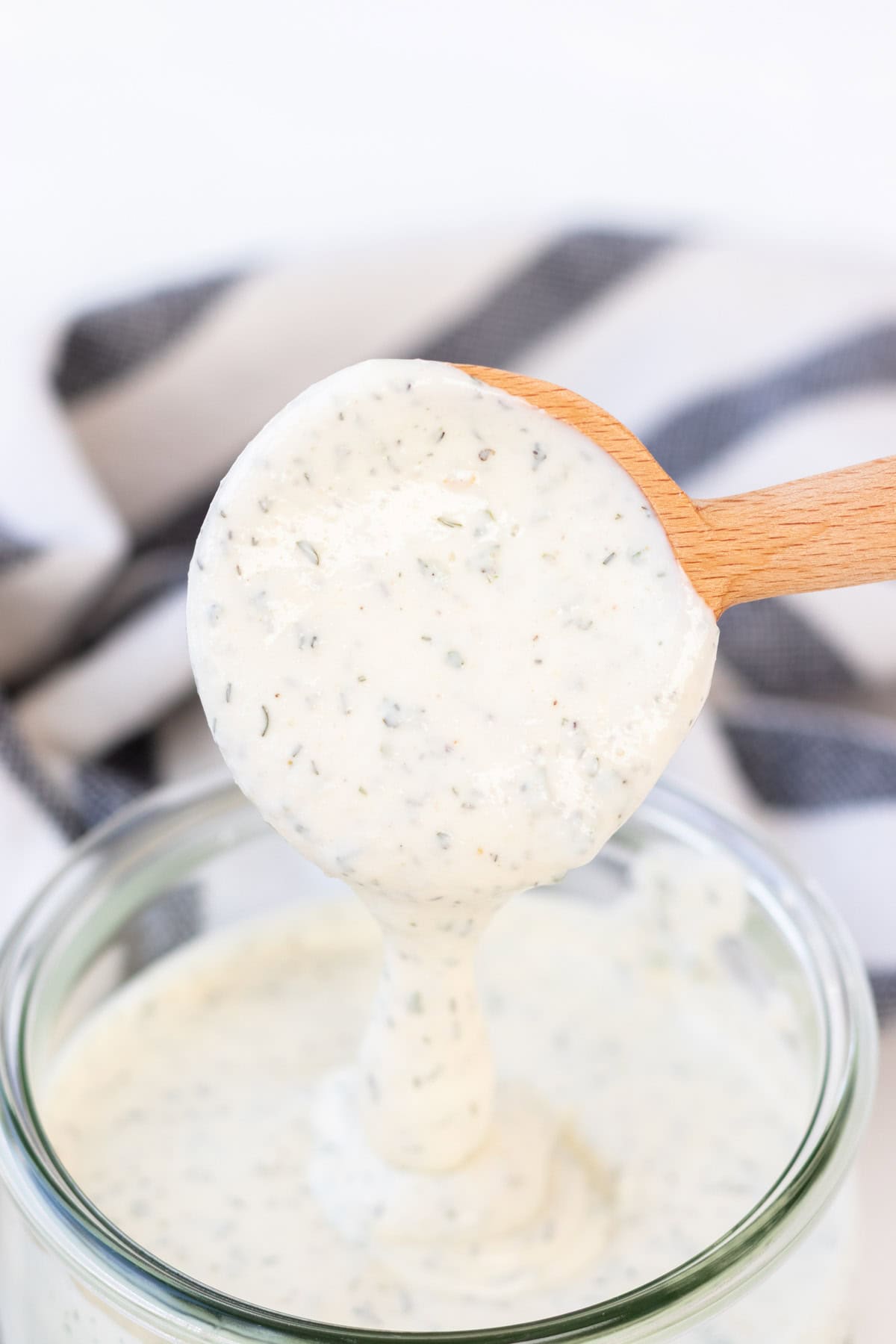 Thick and creamy ranch dressing running off a spoon.
