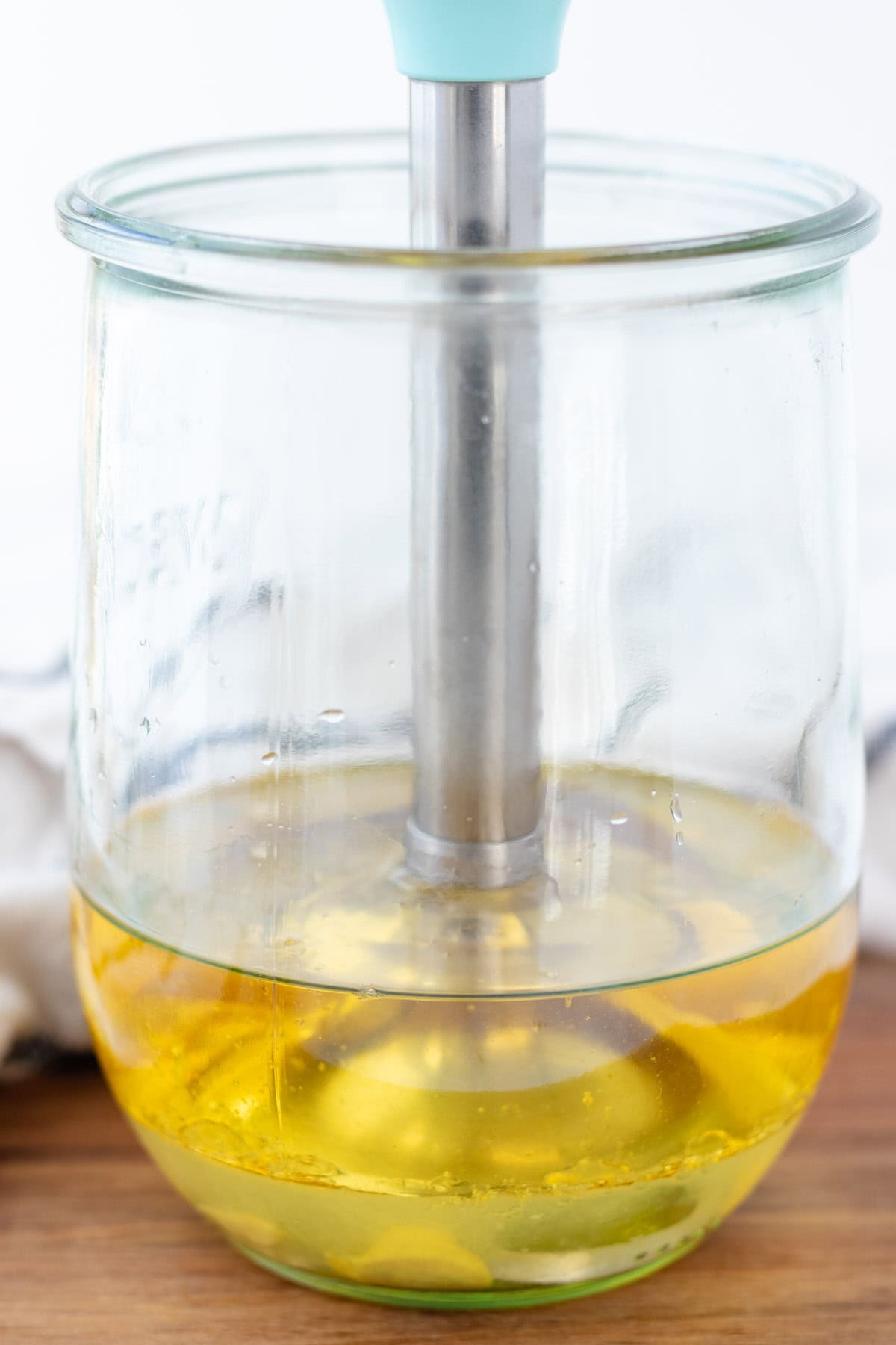 Inserting the immersion blender into the jar, all the way to the bottom.