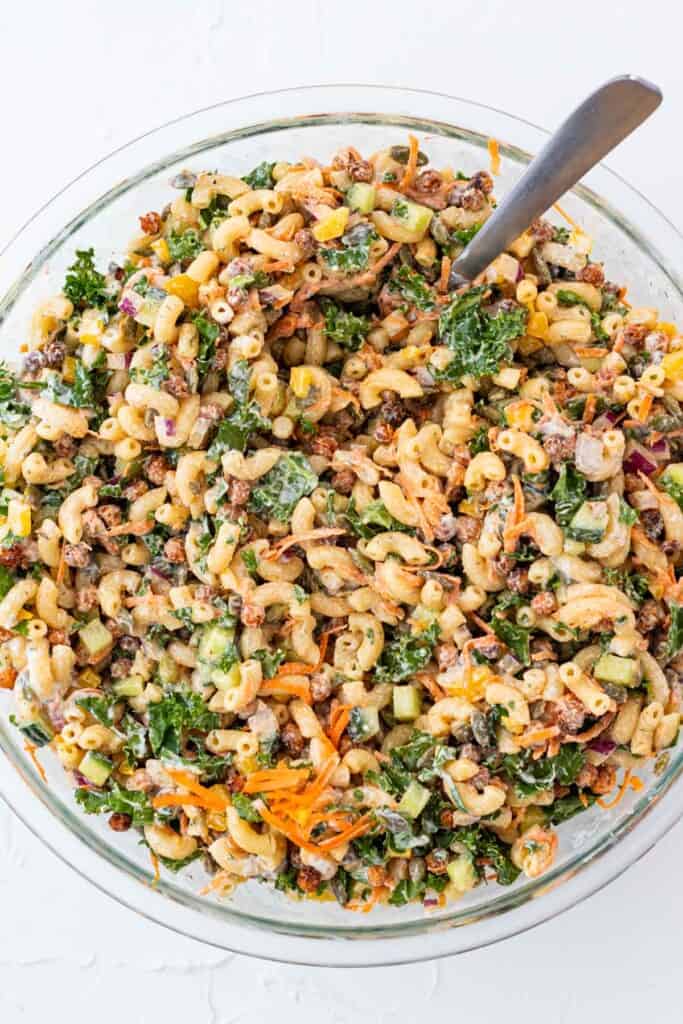 A large glass mixing bowl full of pasta salad with ranch.