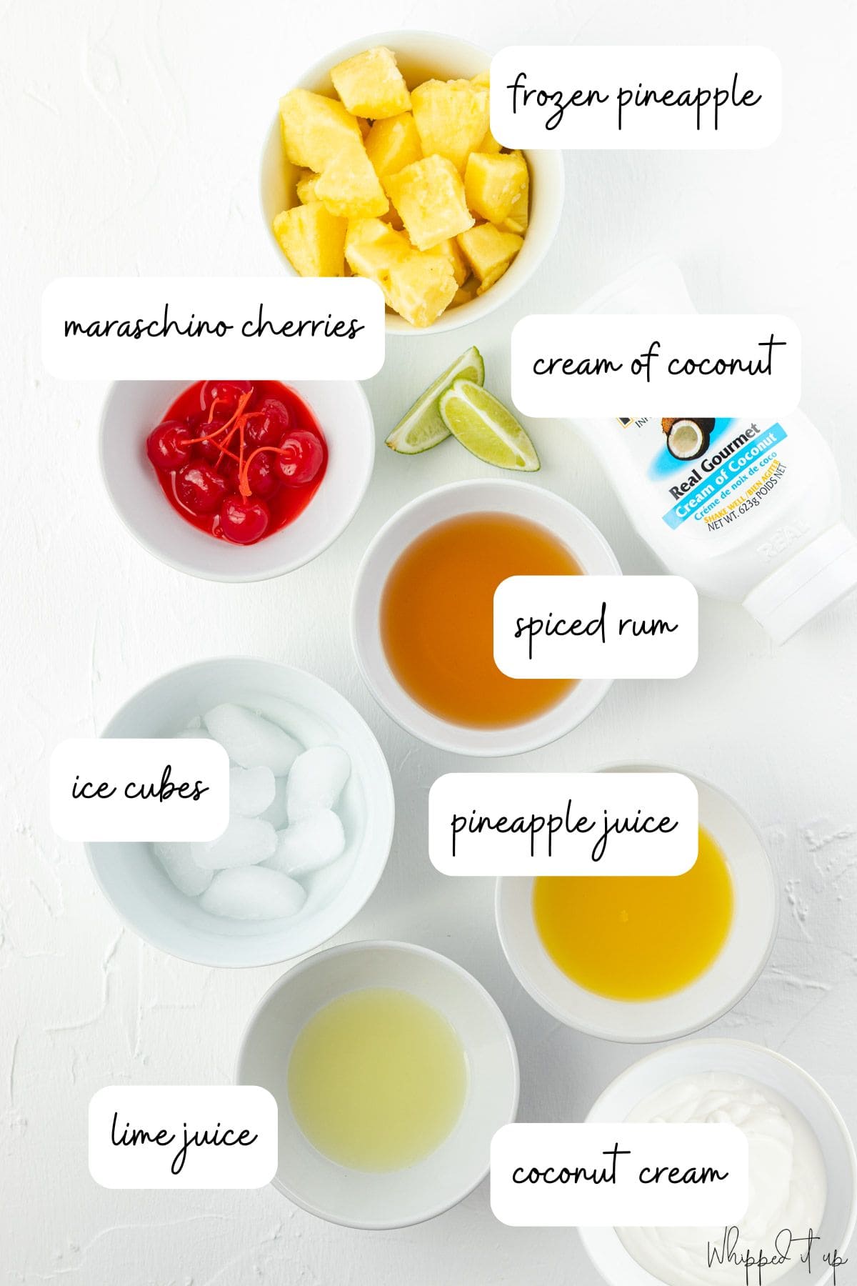 Ingredients include frozen pineapple, maraschino cherries, cream of coconut, spiced rum, ice cubes, pineapple juice, lime juice, and coconut cream.