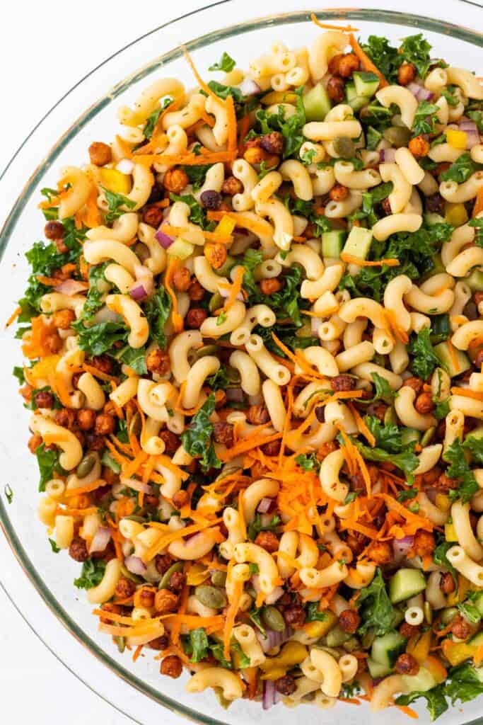 Mixing the pasta salad ingredients in a glass mixing bowl.