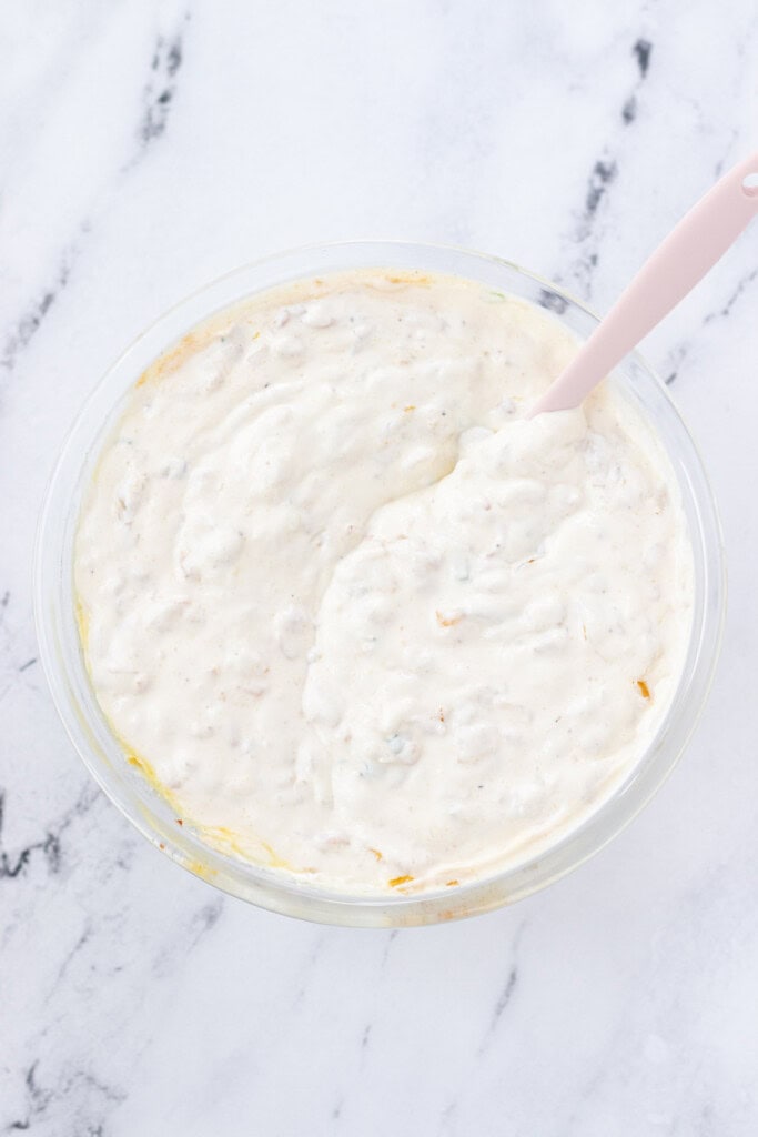 Chip dip stirred up in a mixing bowl with a spatula on the side.