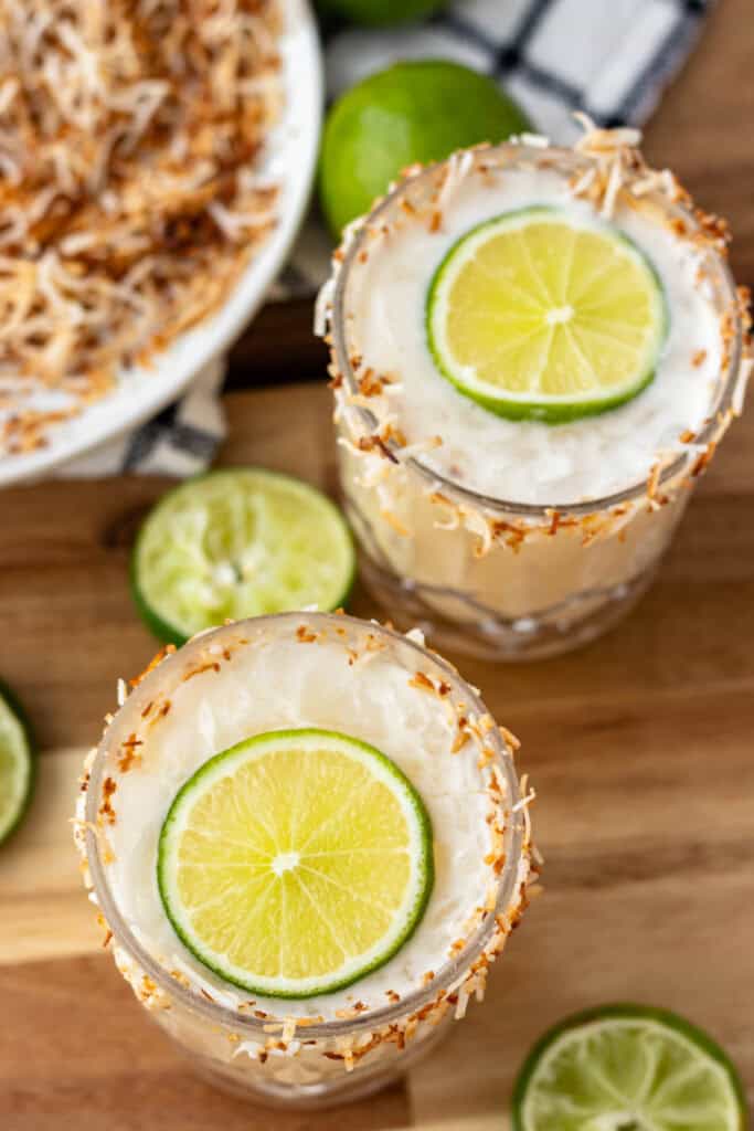 Two toasted coconut margaritas with lime slices.