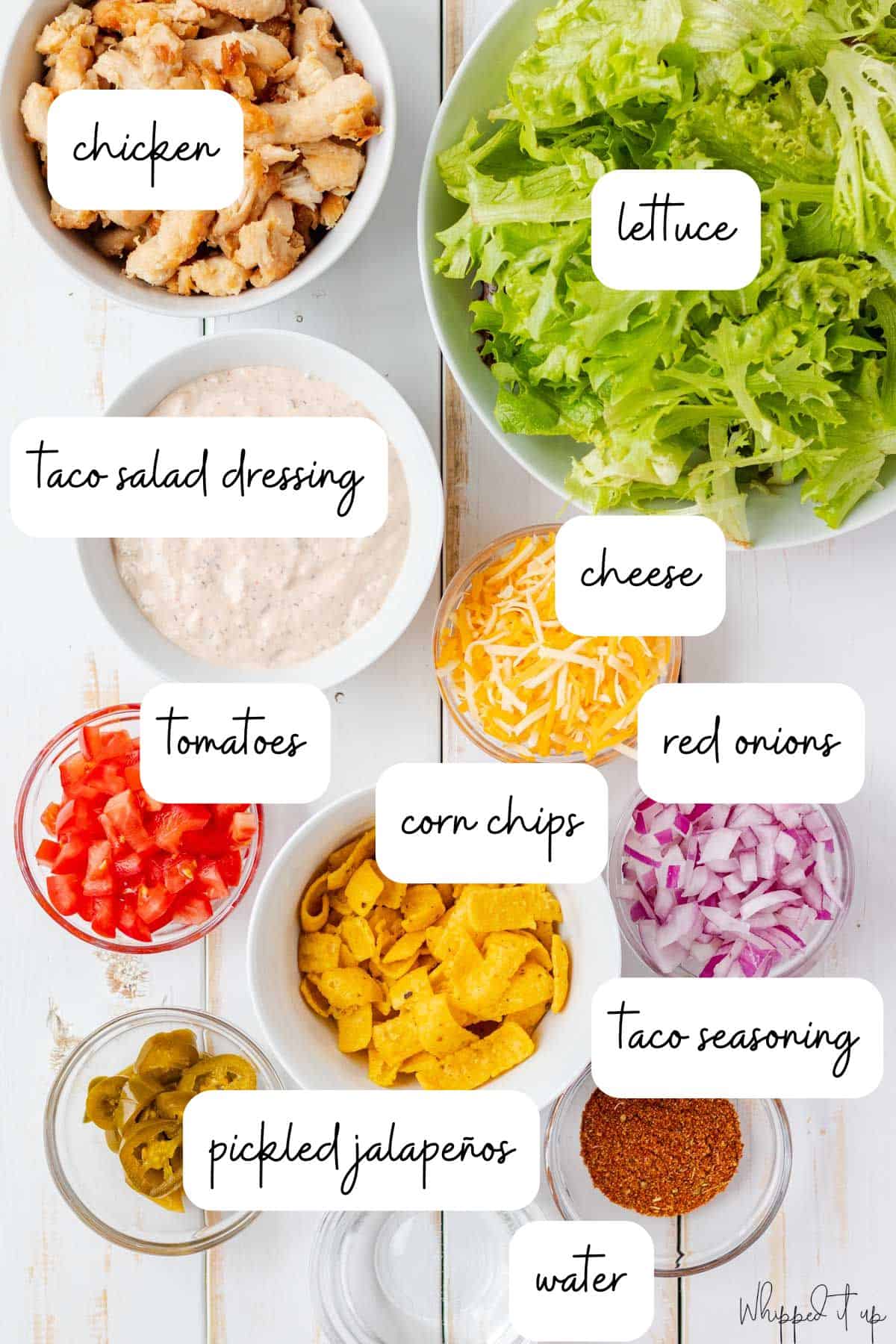 Ingredients for chicken taco salad measured in bowls and laid on a white background.
