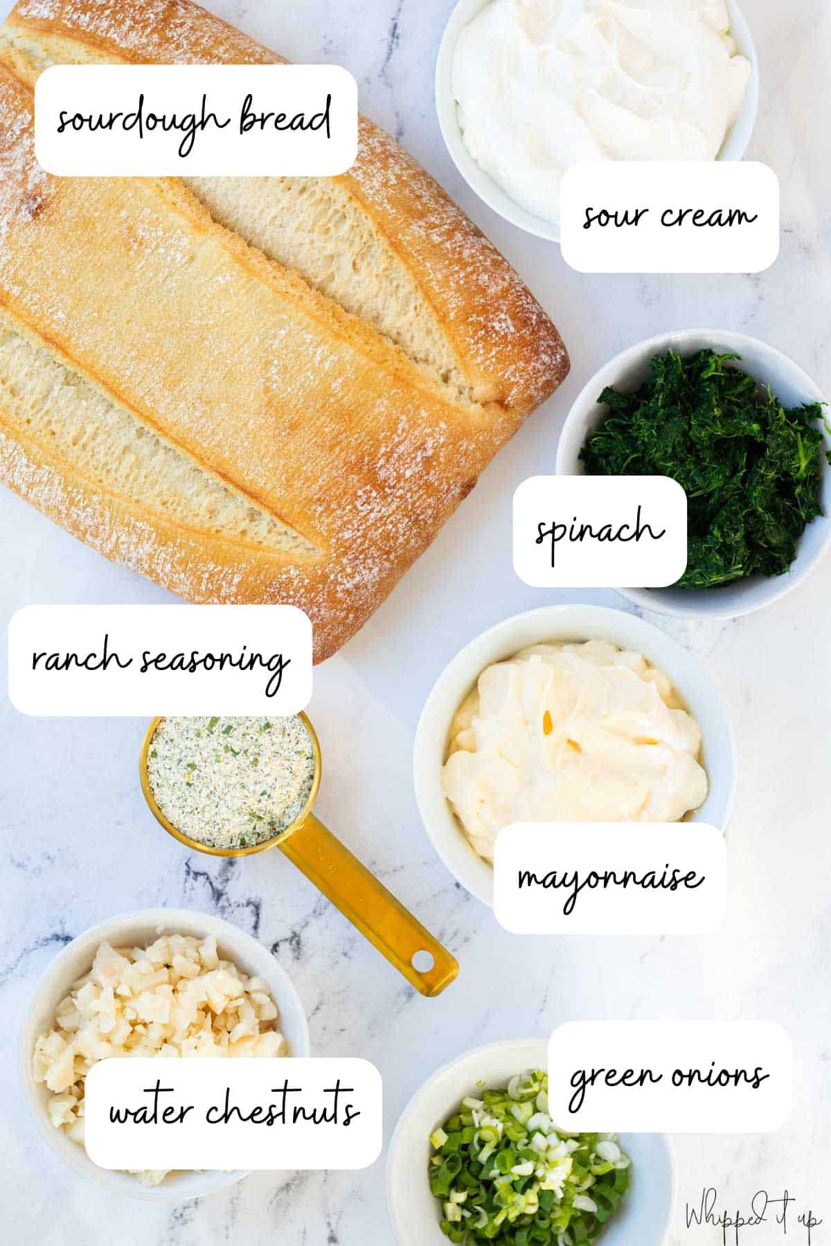 Ingredients to make spinach dip laid out in white bowls on a counter.