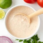 A white bowl full of taco salad dressing with a spoon.