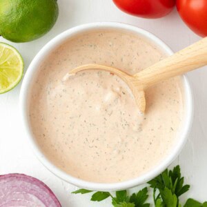 A white bowl full of taco salad dressing with a spoon.