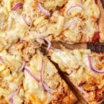 A slice of teriyaki chicken and pineapple pizza being pulled out.