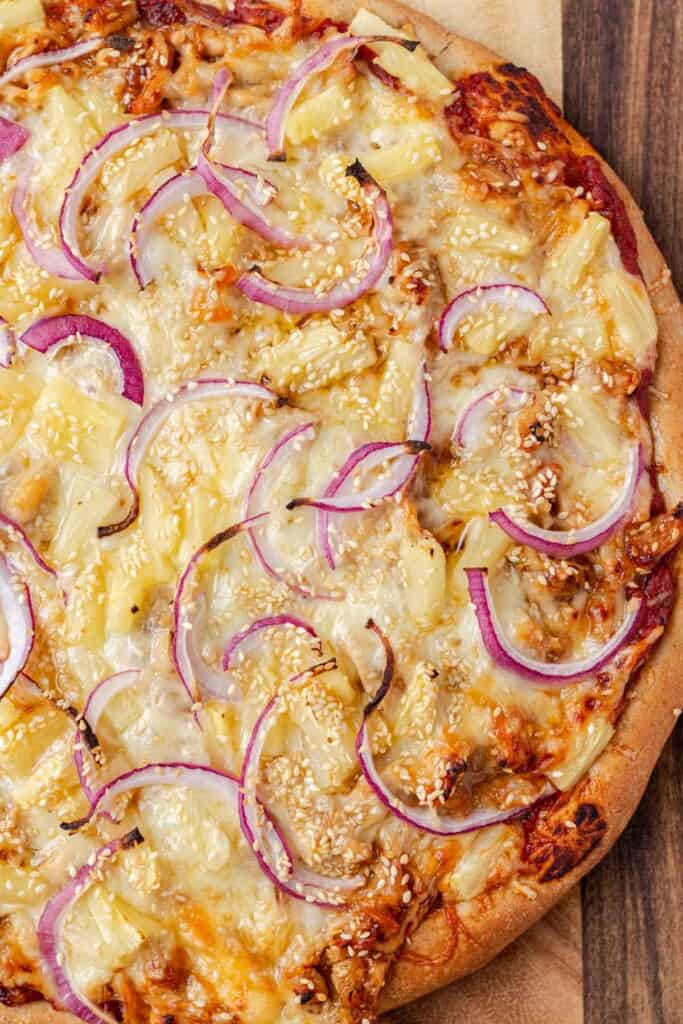 Freshly baked teriyaki chicken pizza on a cutting board.