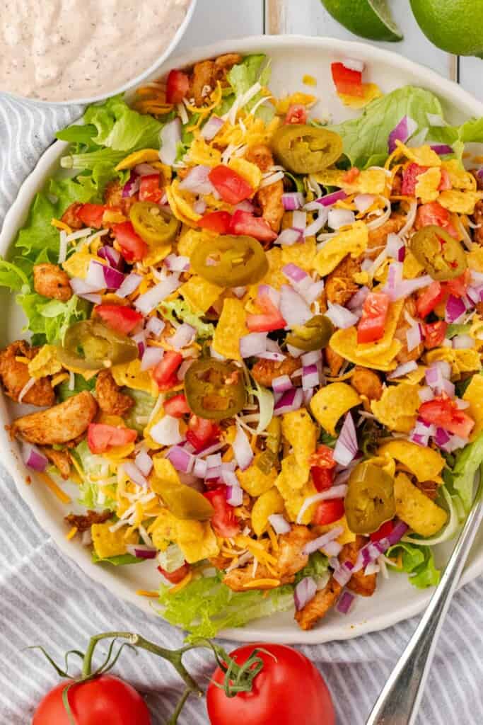 Layering the ingredients on a plate to make taco salad.