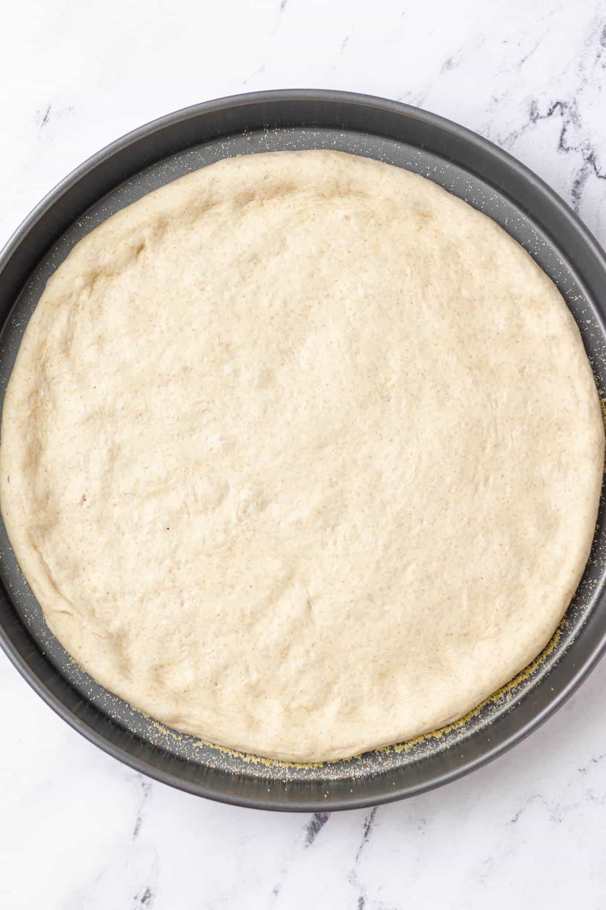 Pressing the pizza dough into the baking pan.