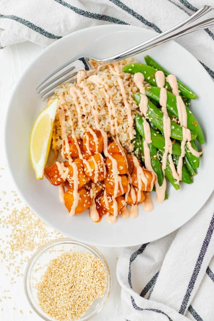 Topping the bowl with spicy mayo drizzle, toasted sesame seeds and a fresh lemon wedge.