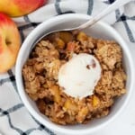 A bowl of old fashioned apple crisp with a scoop of ice cream on top.