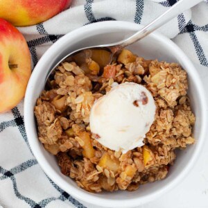 A bowl of old fashioned apple crisp with a scoop of ice cream on top.