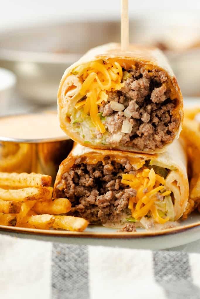 A Big Mac wrap stacked on a plate with fries.