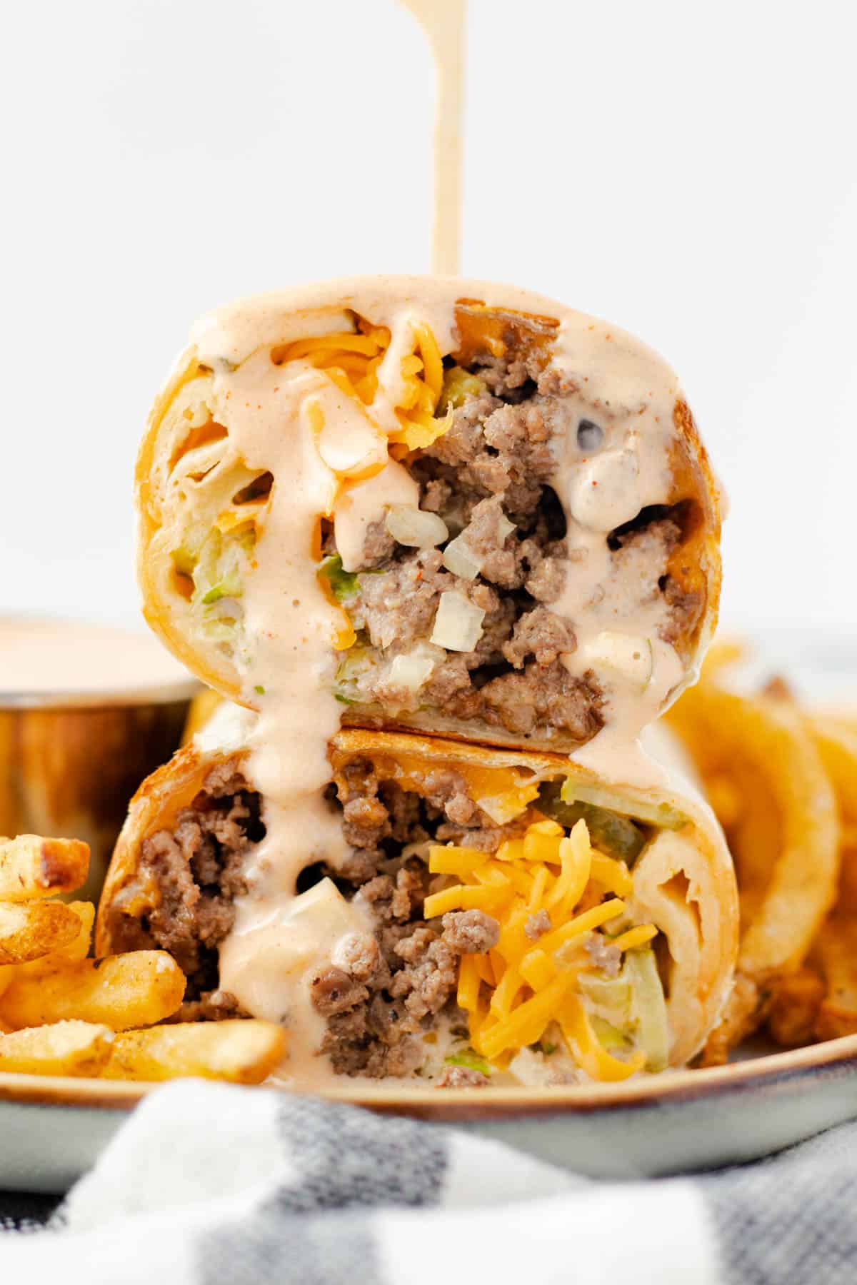 A big mac wrap stacked with a toothpick and sauce running down.