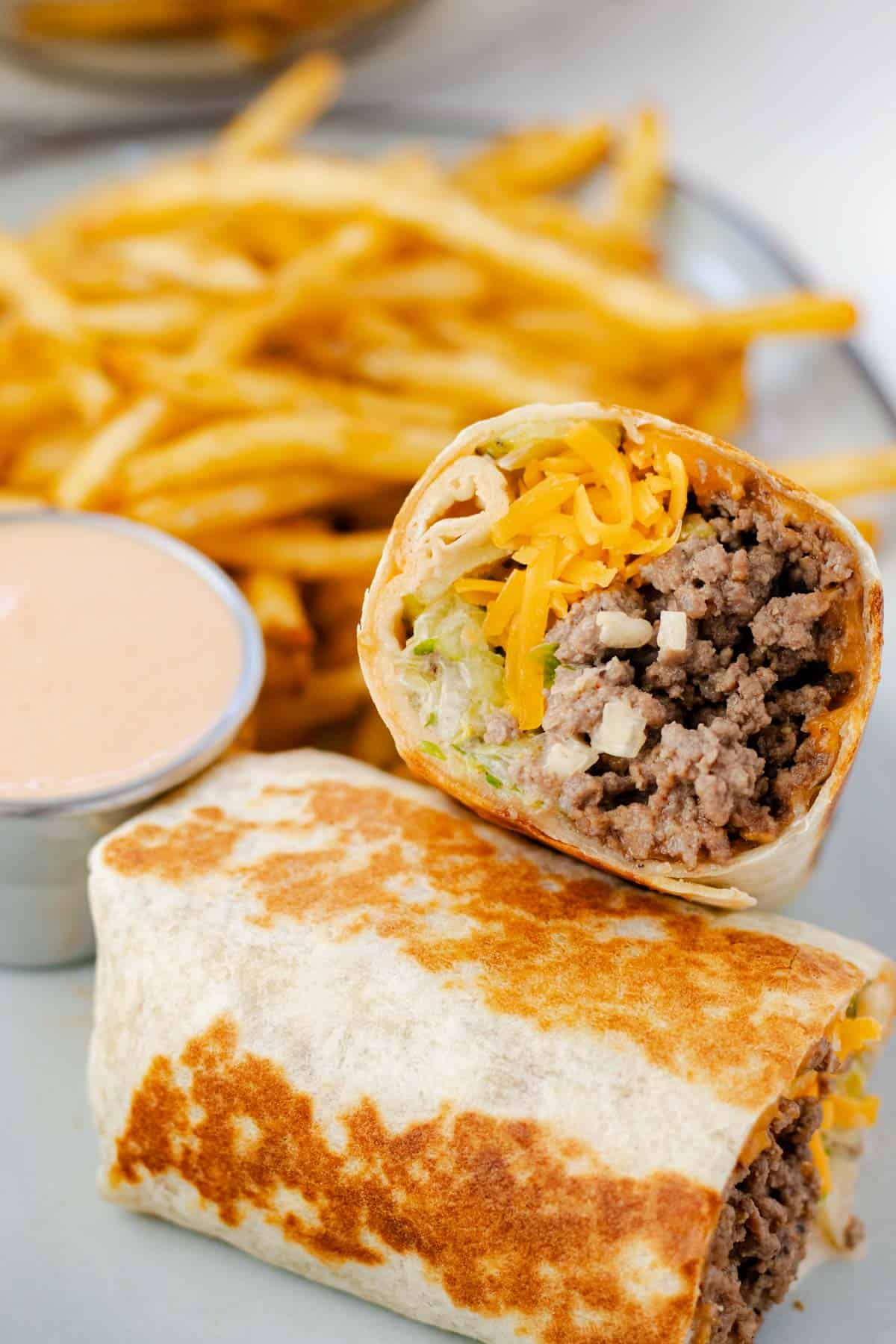 Big Mac wrap toasted on a plate with fries and a side of Big Mac sauce.