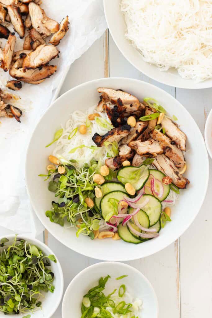 Building a vermicelli bowl in a white bowl, layering the ingredients.