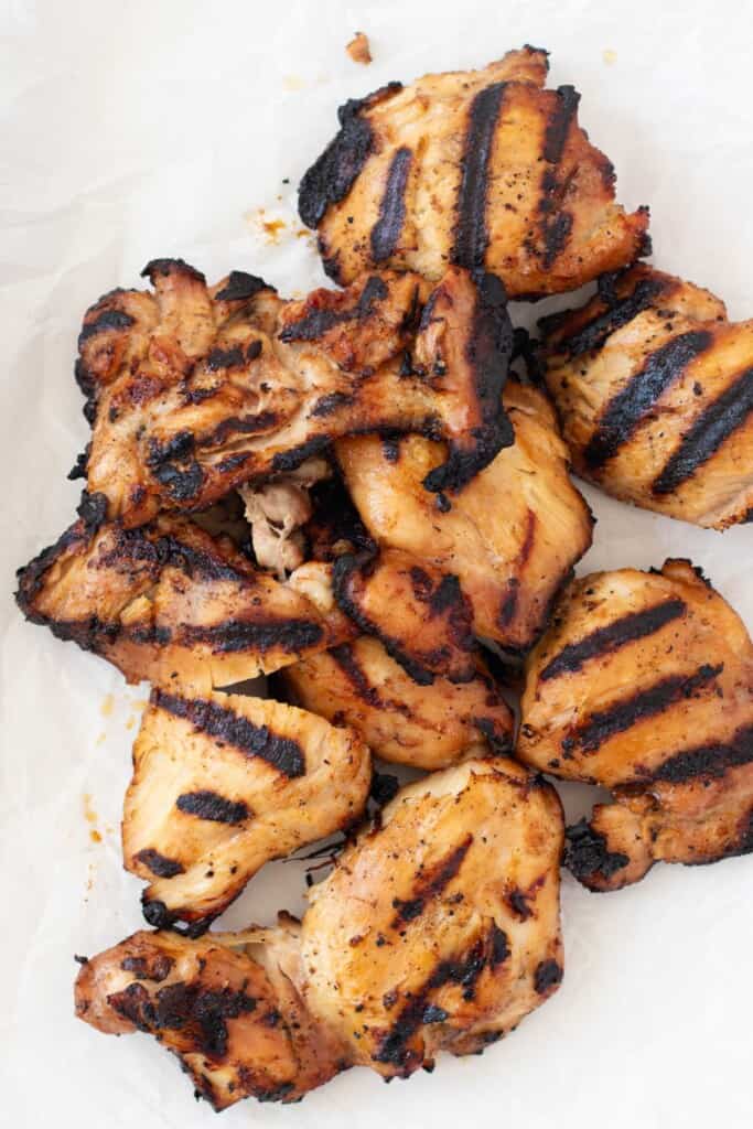 A pile of grilled chicken thighs with black grill marks on the outside.