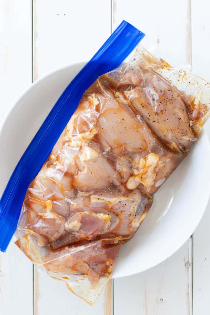 Chicken thighs mixed with marinade in a zip top bag.