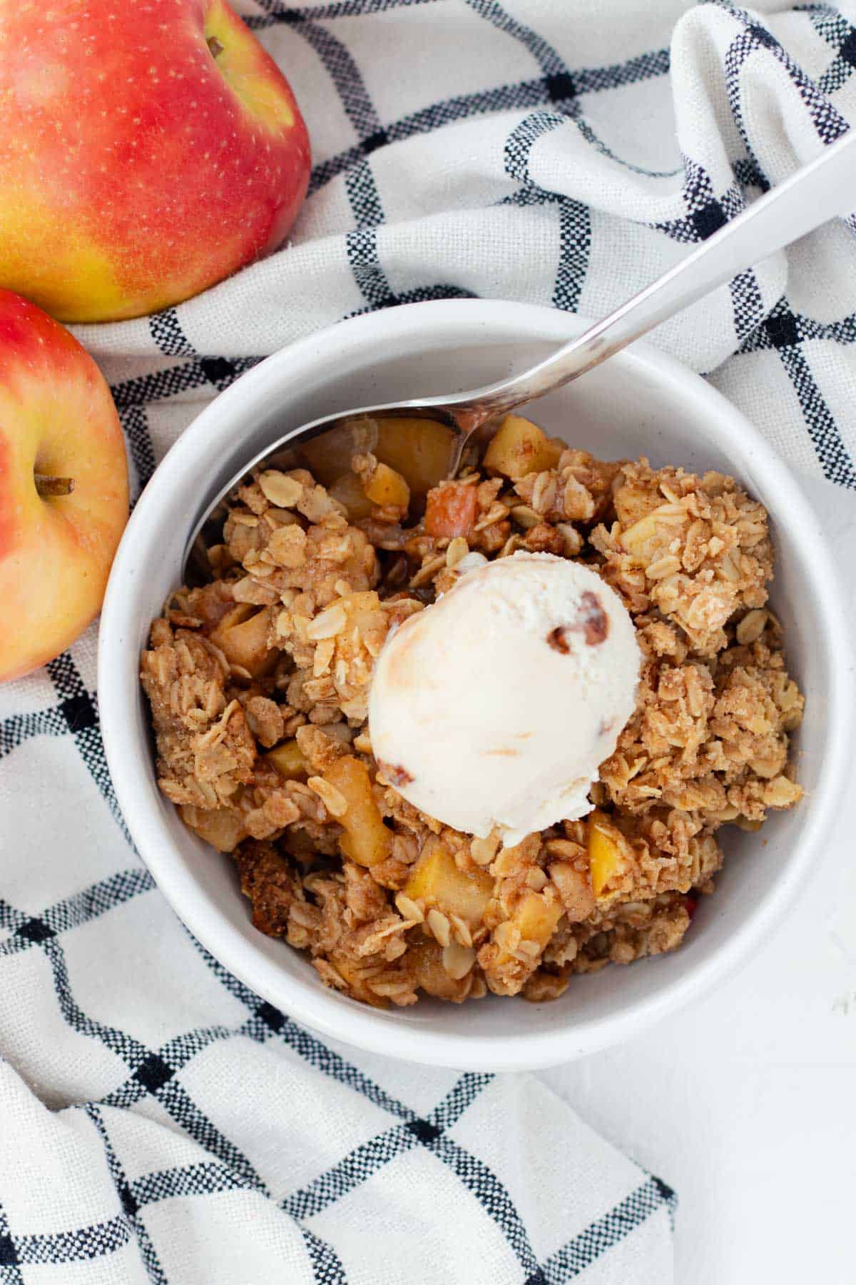 A bowl of old fashioned apple crisp with a scoop of ice cream on top.