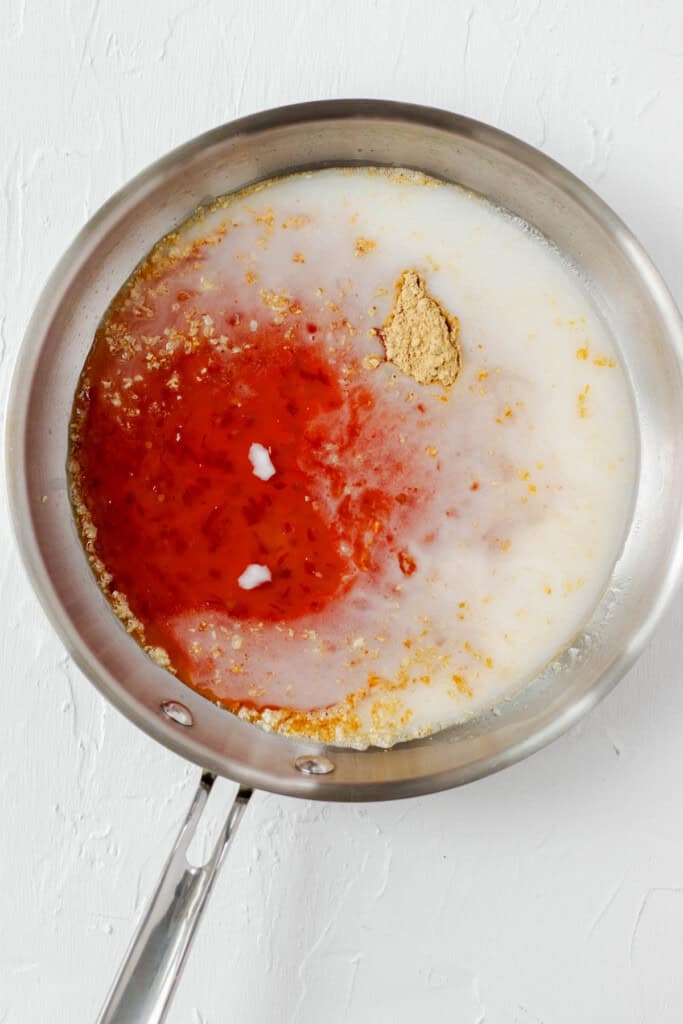 Adding all of the ingredients to make the sweet chili sauce into a stainless steel saucepan.