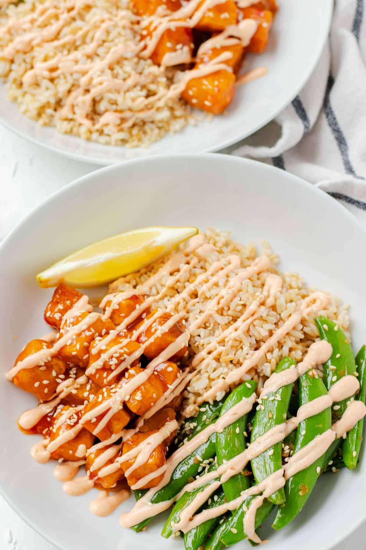 A close up of a sweet chili tofu bowl coated in spicy mayo.