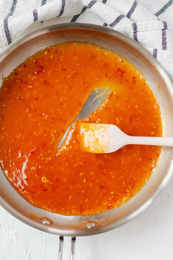 A large skillet filled with thickened sweet chili sauce.
