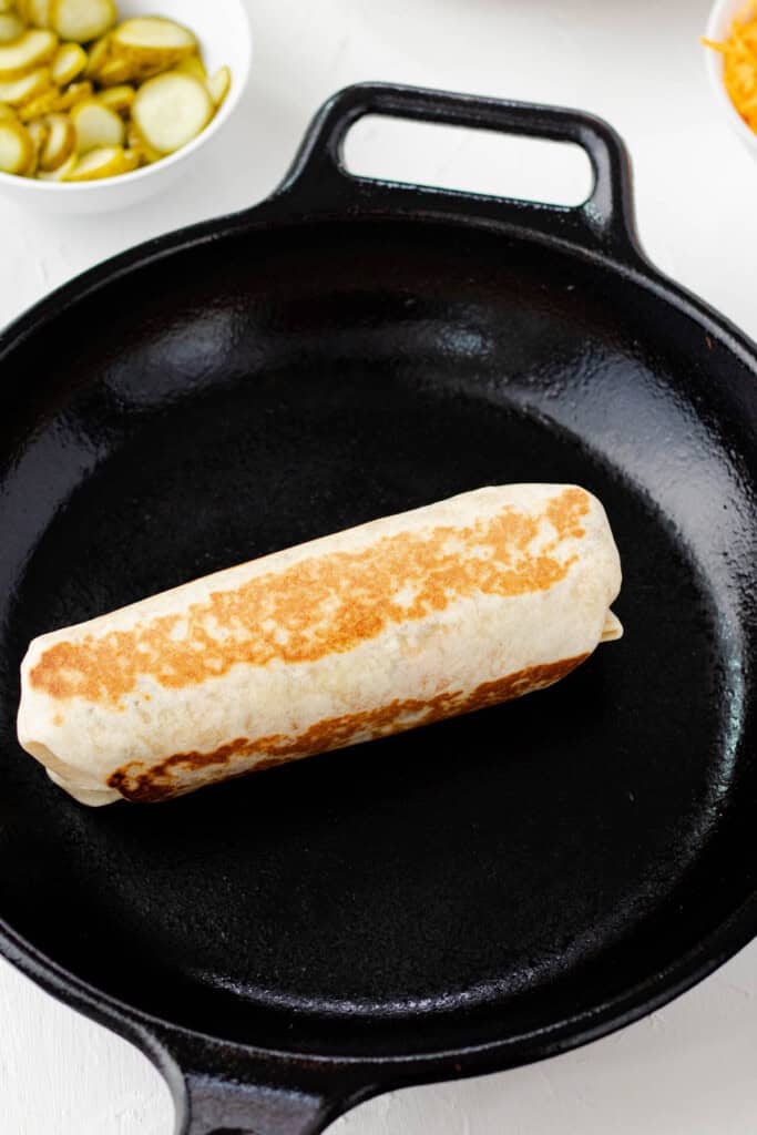 A Big Mac wrap folded and toasted in a cast iron pan until golden brown.