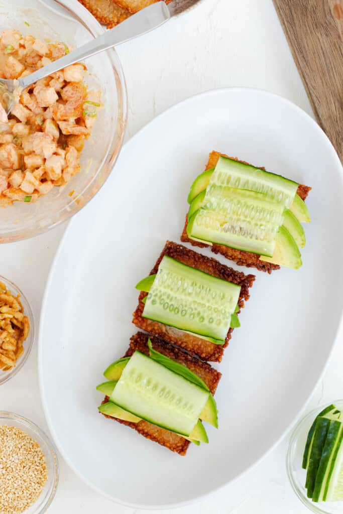 Adding cucumber on top of the avocado.