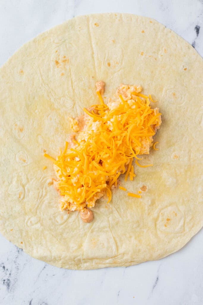 The first layer of the breakfast burrito is layered onto a flour tortilla.