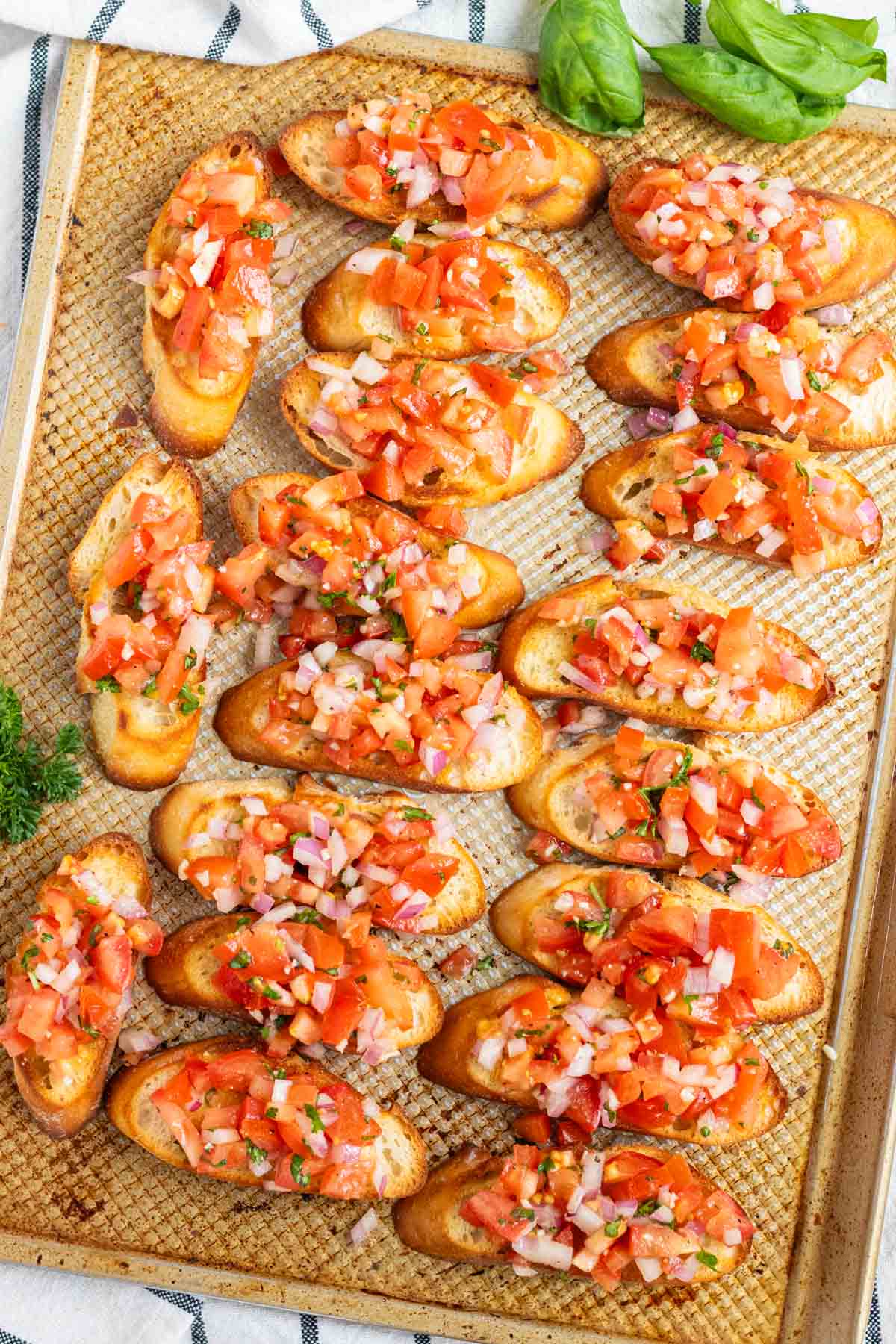 Multiple bruschetta toasts on a large baking sheet.