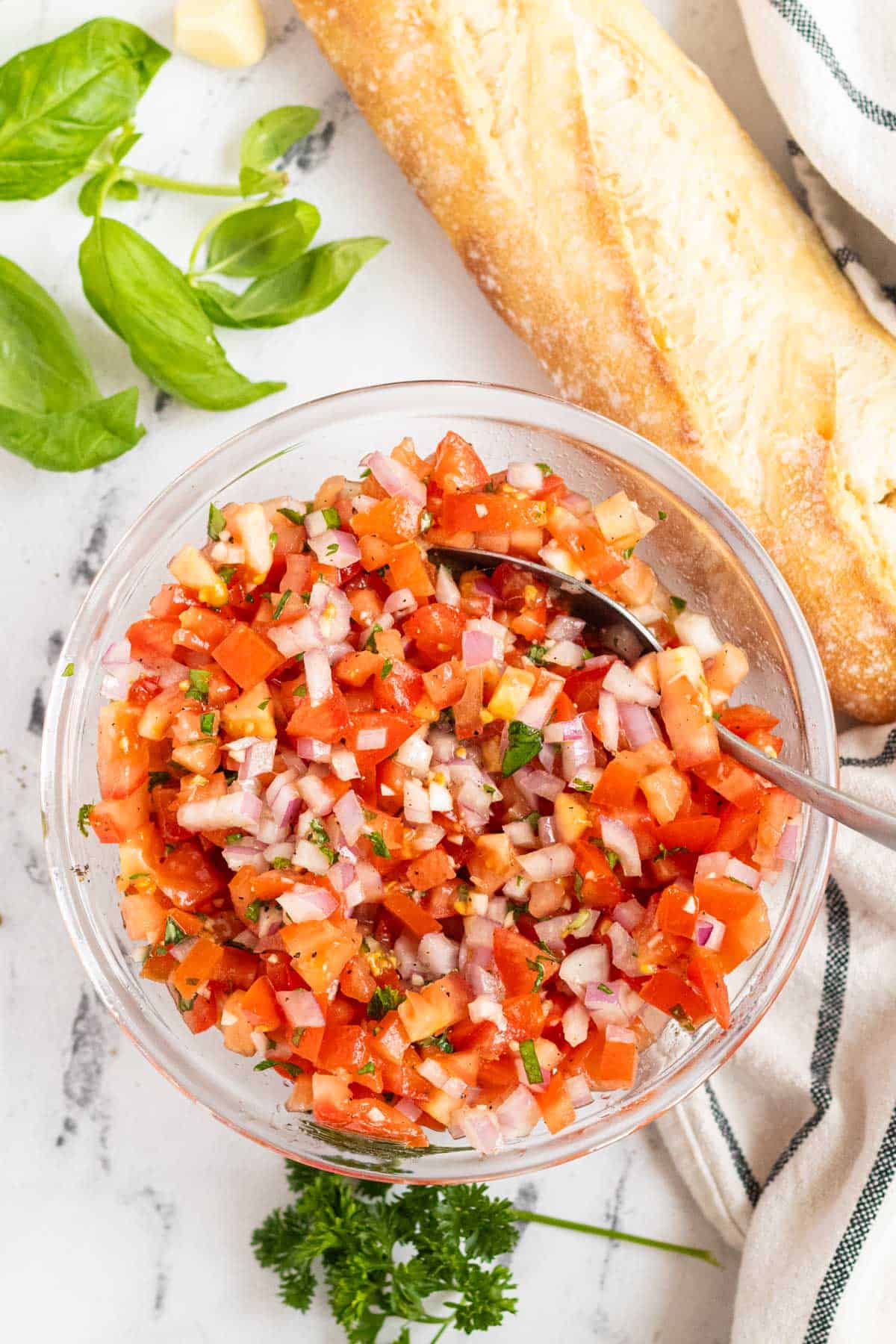 Mixing the tomato bruschetta in a glass bowl.