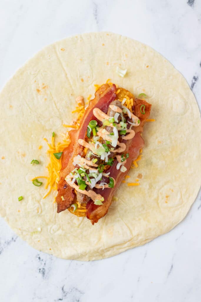 The rest of the breakfast burrito toppings are added to the tortilla.